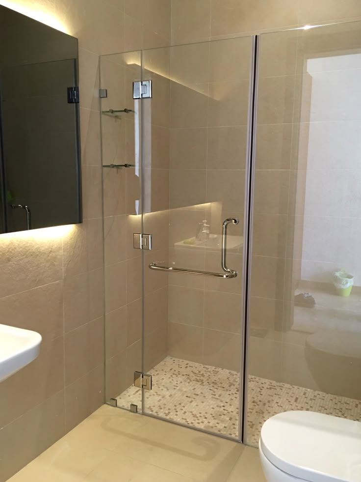 Frameless hinged shower door in a warm-lit modern bathroom