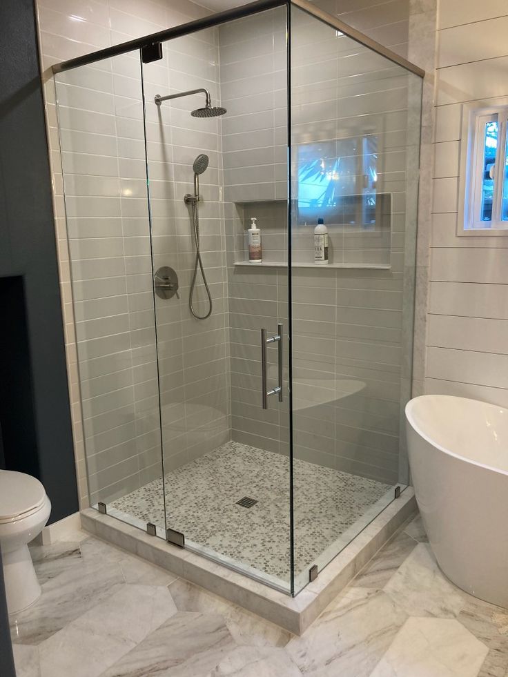 Large frameless shower cubicle beside a freestanding bathtub