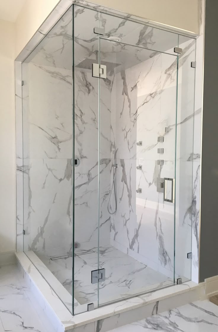 Full marble bathroom with custom angled frameless shower enclosure